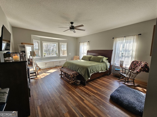 bedroom with ceiling fan, dark hardwood / wood-style floors, and a textured ceiling