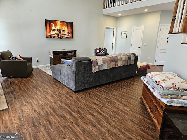 living room featuring a towering ceiling and dark hardwood / wood-style floors