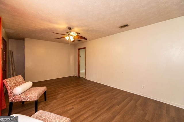 unfurnished room featuring ceiling fan, dark hardwood / wood-style floors, and a textured ceiling