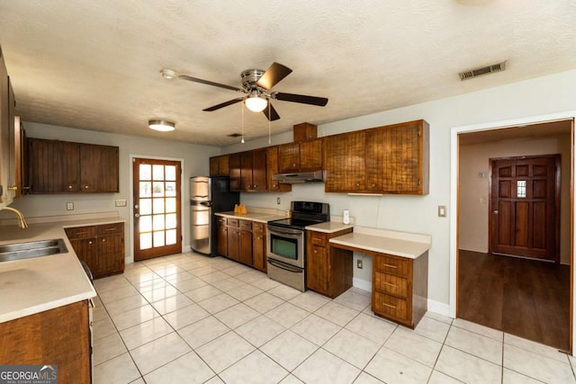 kitchen featuring sink, light tile patterned floors, ceiling fan, appliances with stainless steel finishes, and a textured ceiling