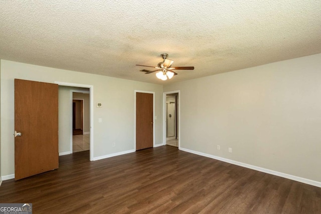 empty room with dark hardwood / wood-style floors, a textured ceiling, and ceiling fan