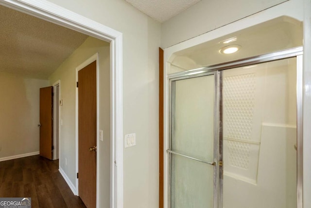 bathroom with hardwood / wood-style floors, a textured ceiling, and walk in shower