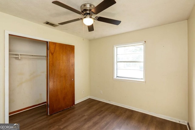 unfurnished bedroom featuring dark wood-type flooring, a textured ceiling, ceiling fan, and a closet