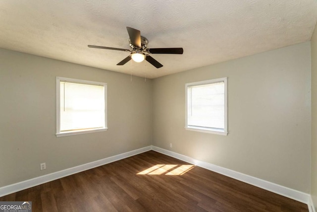 empty room featuring ceiling fan, dark wood-type flooring, and a textured ceiling