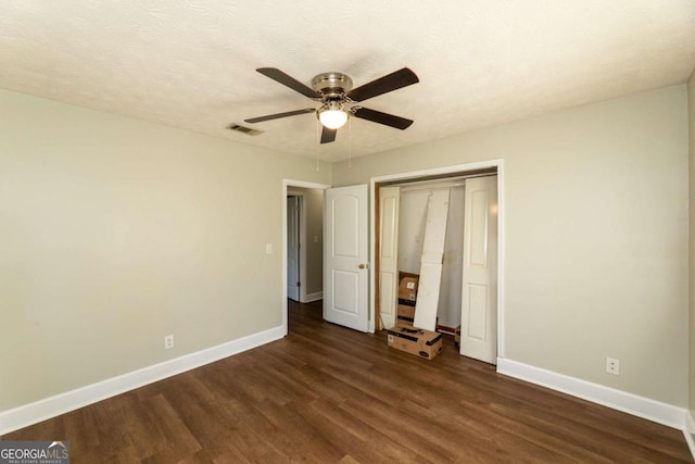 unfurnished bedroom featuring ceiling fan, dark hardwood / wood-style floors, a closet, and a textured ceiling