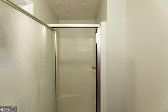 bathroom featuring walk in shower and a textured ceiling