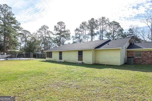 rear view of house with central AC and a lawn