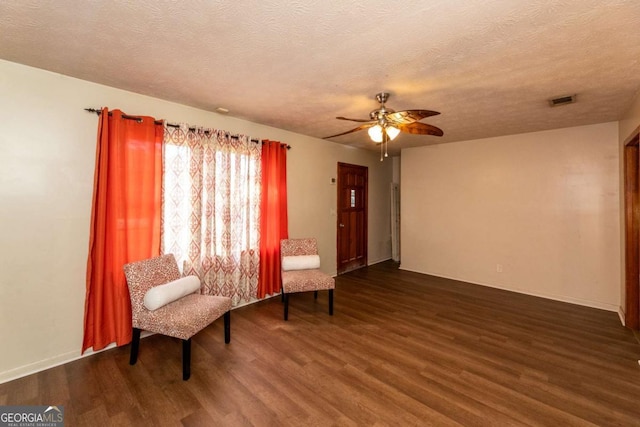 living area featuring ceiling fan, dark hardwood / wood-style floors, and a textured ceiling