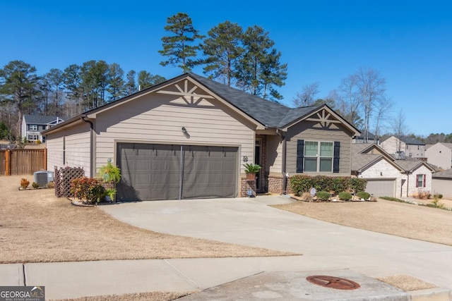 view of front facade with driveway, central AC unit, an attached garage, fence, and brick siding