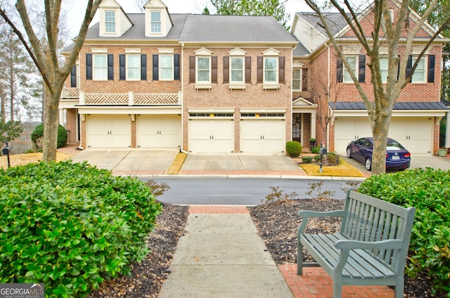 multi unit property featuring driveway, brick siding, and roof with shingles