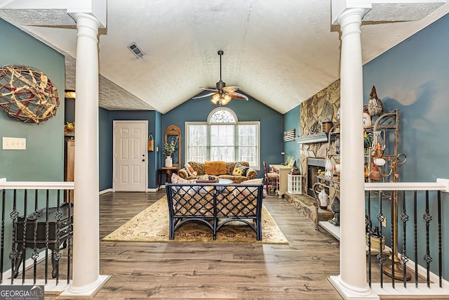 entrance foyer with ceiling fan, hardwood / wood-style floors, a textured ceiling, and ornate columns