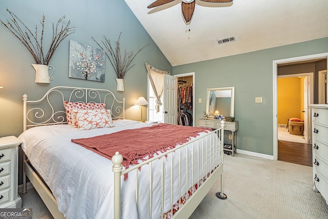 carpeted bedroom with a walk in closet, a closet, ceiling fan, and vaulted ceiling