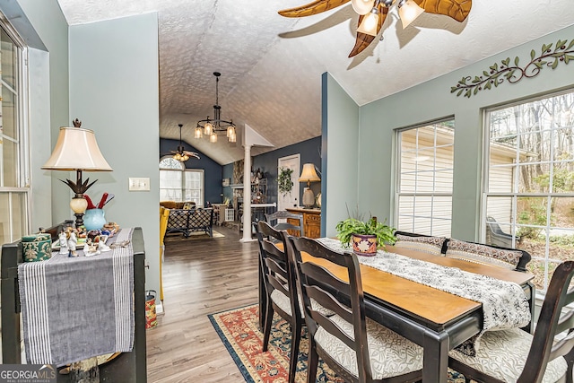 dining room featuring ceiling fan, lofted ceiling, a textured ceiling, and light wood-type flooring