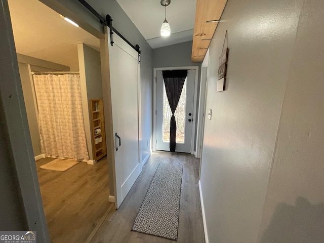 entryway featuring hardwood / wood-style floors, vaulted ceiling, and a barn door