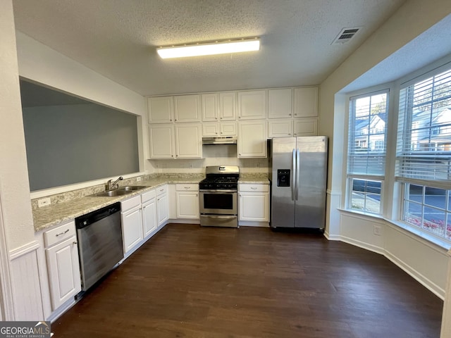 kitchen featuring sink, a textured ceiling, appliances with stainless steel finishes, dark hardwood / wood-style flooring, and white cabinets