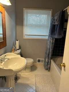 bathroom with toilet, curtained shower, and tile patterned flooring