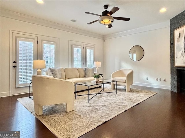 living room featuring crown molding, a fireplace, dark hardwood / wood-style floors, and ceiling fan