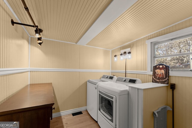 clothes washing area featuring washer and clothes dryer and light hardwood / wood-style flooring