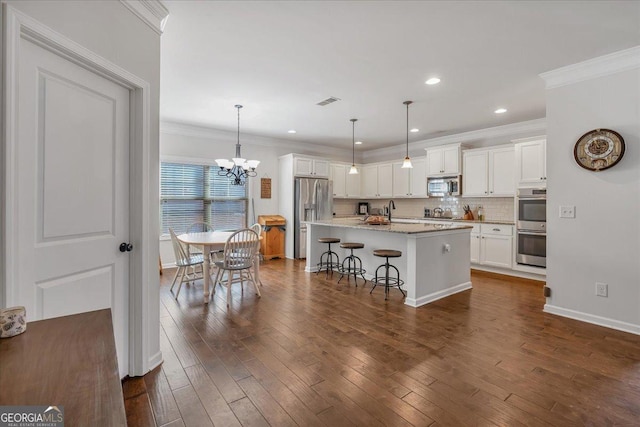 3890 Pleasant Woods Dr, Cumming, GA 30028 - kitchen with crown molding, stainless steel appliances, decorative backsplash, dark wood-type flooring, and white cabinets