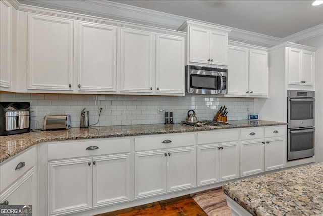 3890 Pleasant Woods Dr, Cumming, GA 30028 - kitchen featuring stone countertops, white cabinets, ornamental molding, appliances with stainless steel finishes, and backsplash