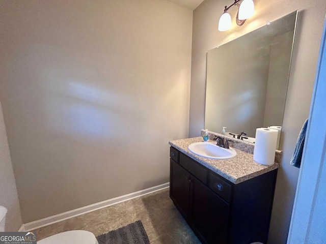 bathroom with vanity, toilet, and baseboards