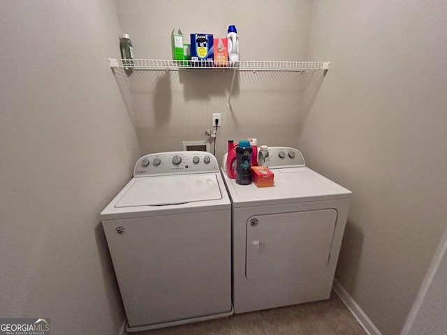 clothes washing area with baseboards, wood finished floors, laundry area, and washing machine and clothes dryer