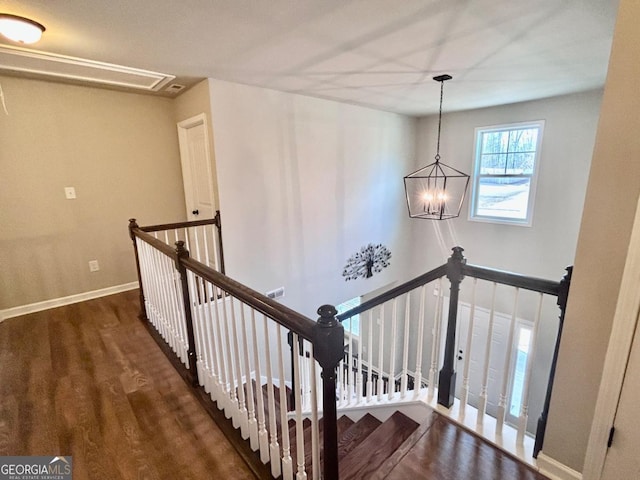 stairway featuring wood finished floors, baseboards, and a chandelier