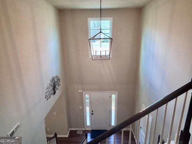 foyer with baseboards, a chandelier, stairs, a towering ceiling, and wood finished floors