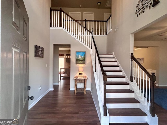 stairway with baseboards, a high ceiling, and wood finished floors