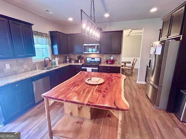 kitchen featuring a sink, tasteful backsplash, appliances with stainless steel finishes, and light wood-style flooring