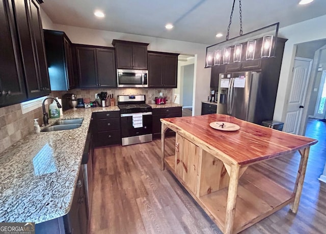 kitchen with backsplash, dark wood-style flooring, appliances with stainless steel finishes, and a sink