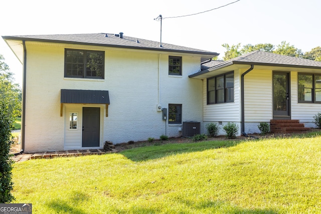 back of property featuring central AC unit and a yard