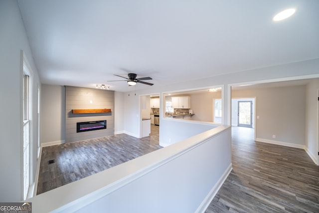 unfurnished living room featuring ceiling fan, a fireplace, and dark hardwood / wood-style flooring