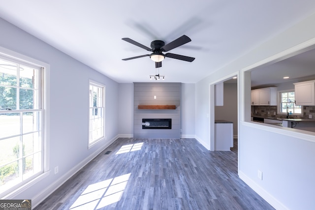 unfurnished living room featuring dark hardwood / wood-style flooring, a fireplace, and plenty of natural light