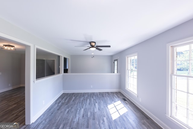 spare room featuring a healthy amount of sunlight, dark wood-type flooring, and ceiling fan