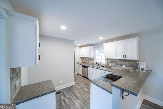 kitchen featuring sink, white cabinetry, tasteful backsplash, stainless steel dishwasher, and kitchen peninsula