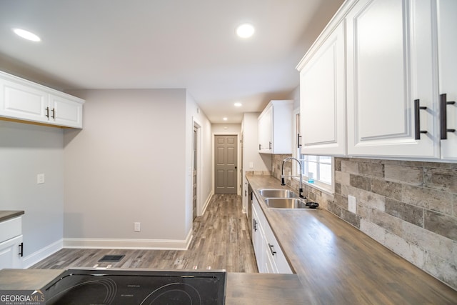 kitchen featuring wood counters, sink, tasteful backsplash, light hardwood / wood-style floors, and white cabinets