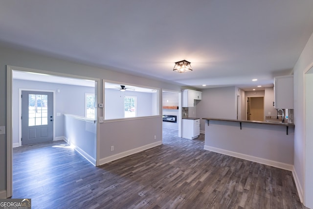 kitchen featuring sink, a breakfast bar area, white cabinetry, dark hardwood / wood-style floors, and kitchen peninsula