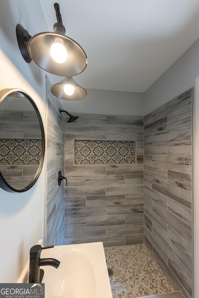 bathroom featuring a tile shower and sink