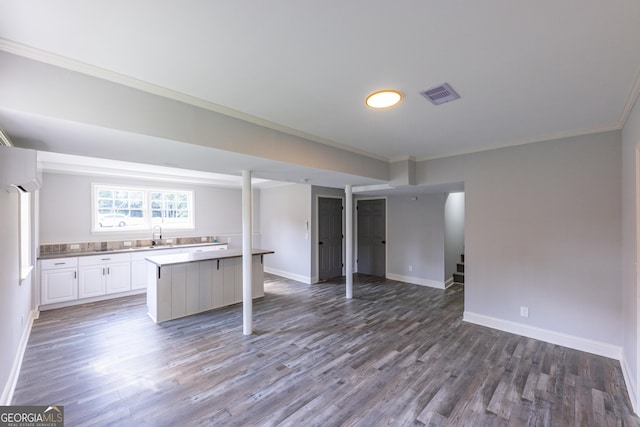 kitchen with sink, white cabinetry, crown molding, wood-type flooring, and a wall mounted AC