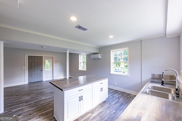 kitchen with white cabinetry, sink, butcher block counters, crown molding, and dark wood-type flooring