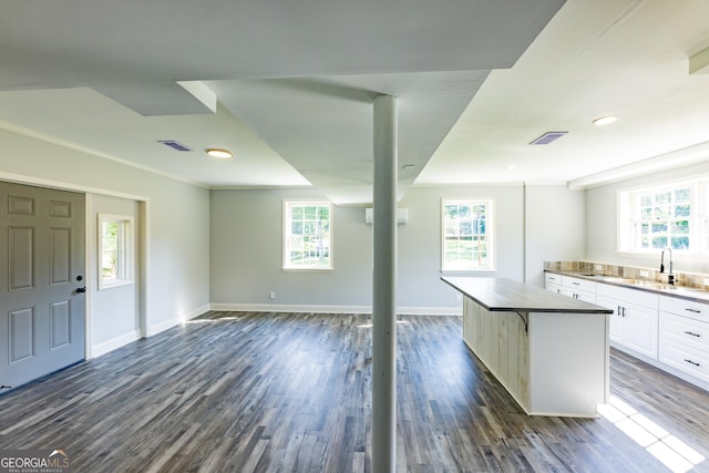 kitchen featuring dark hardwood / wood-style floors, sink, a breakfast bar area, white cabinets, and a center island