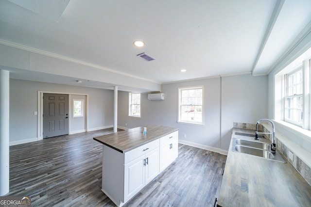 kitchen featuring butcher block counters, sink, white cabinetry, an AC wall unit, and dark hardwood / wood-style floors