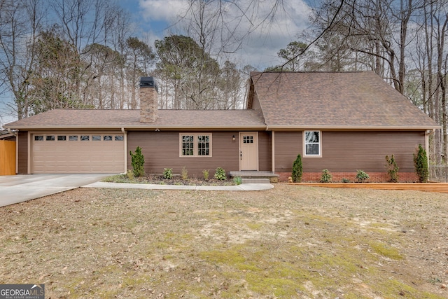 view of front facade with a garage, driveway, a chimney, and roof with shingles