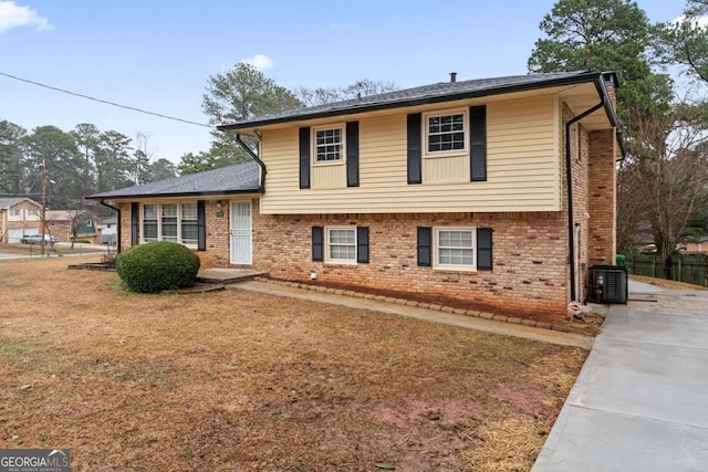 split level home with cooling unit and a front yard