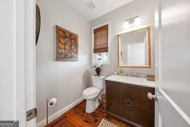 bathroom with wood-type flooring, toilet, and vanity