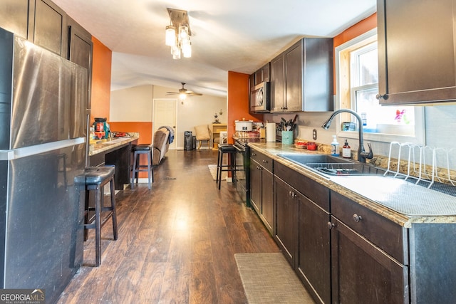 kitchen featuring lofted ceiling, dark brown cabinets, ceiling fan, stainless steel appliances, and dark wood-type flooring