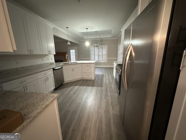 kitchen featuring appliances with stainless steel finishes, a tray ceiling, kitchen peninsula, pendant lighting, and white cabinets