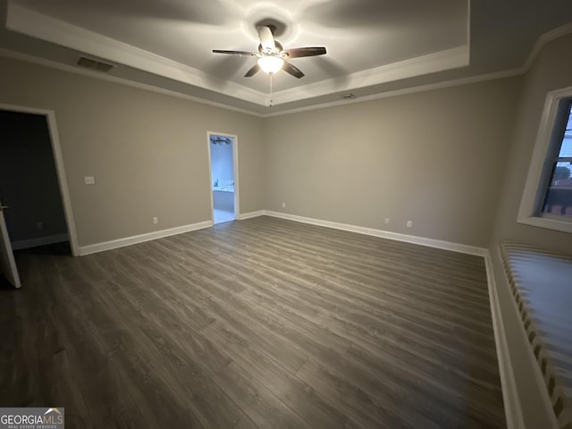 empty room with ceiling fan, ornamental molding, dark hardwood / wood-style flooring, and a raised ceiling