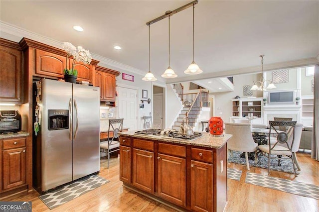 kitchen with a kitchen island, appliances with stainless steel finishes, hanging light fixtures, light hardwood / wood-style floors, and light stone countertops